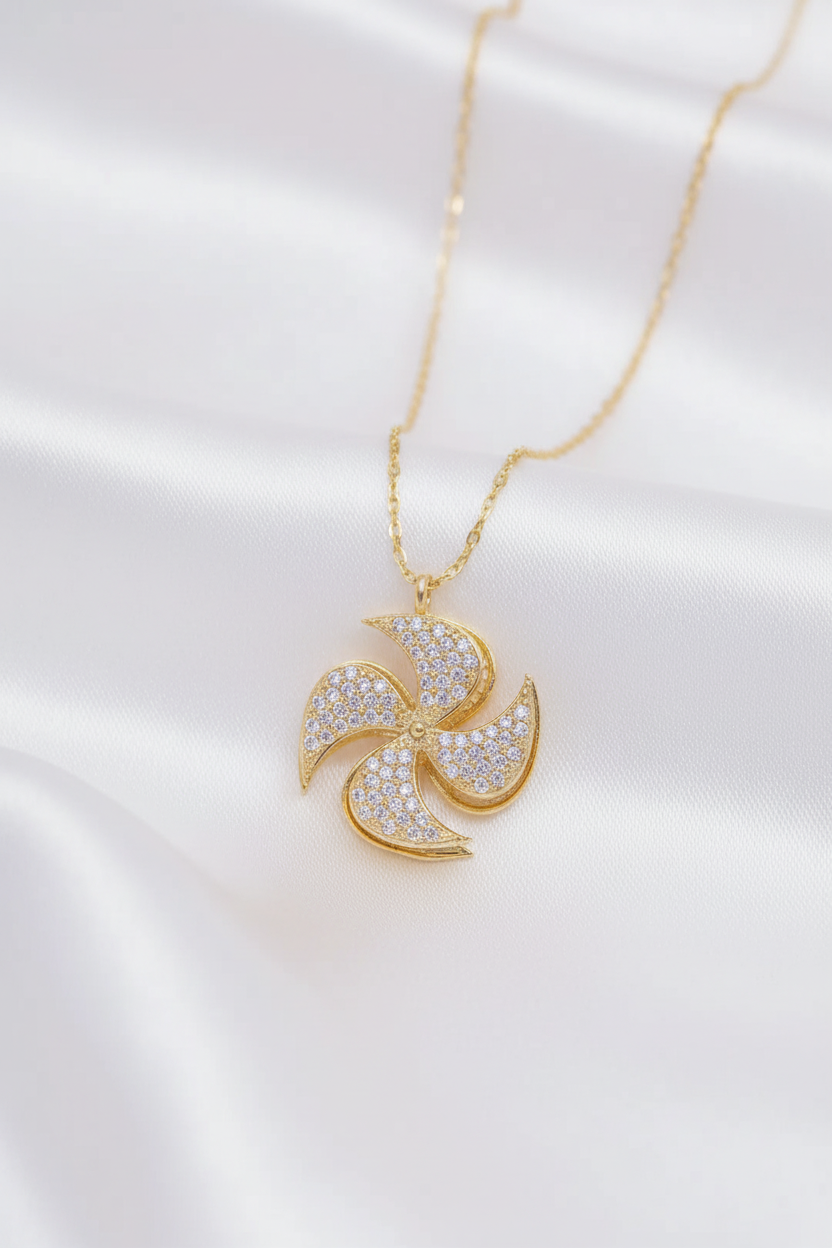 Beyaz saten arka planda altın kaplama yel değirmeni kolye